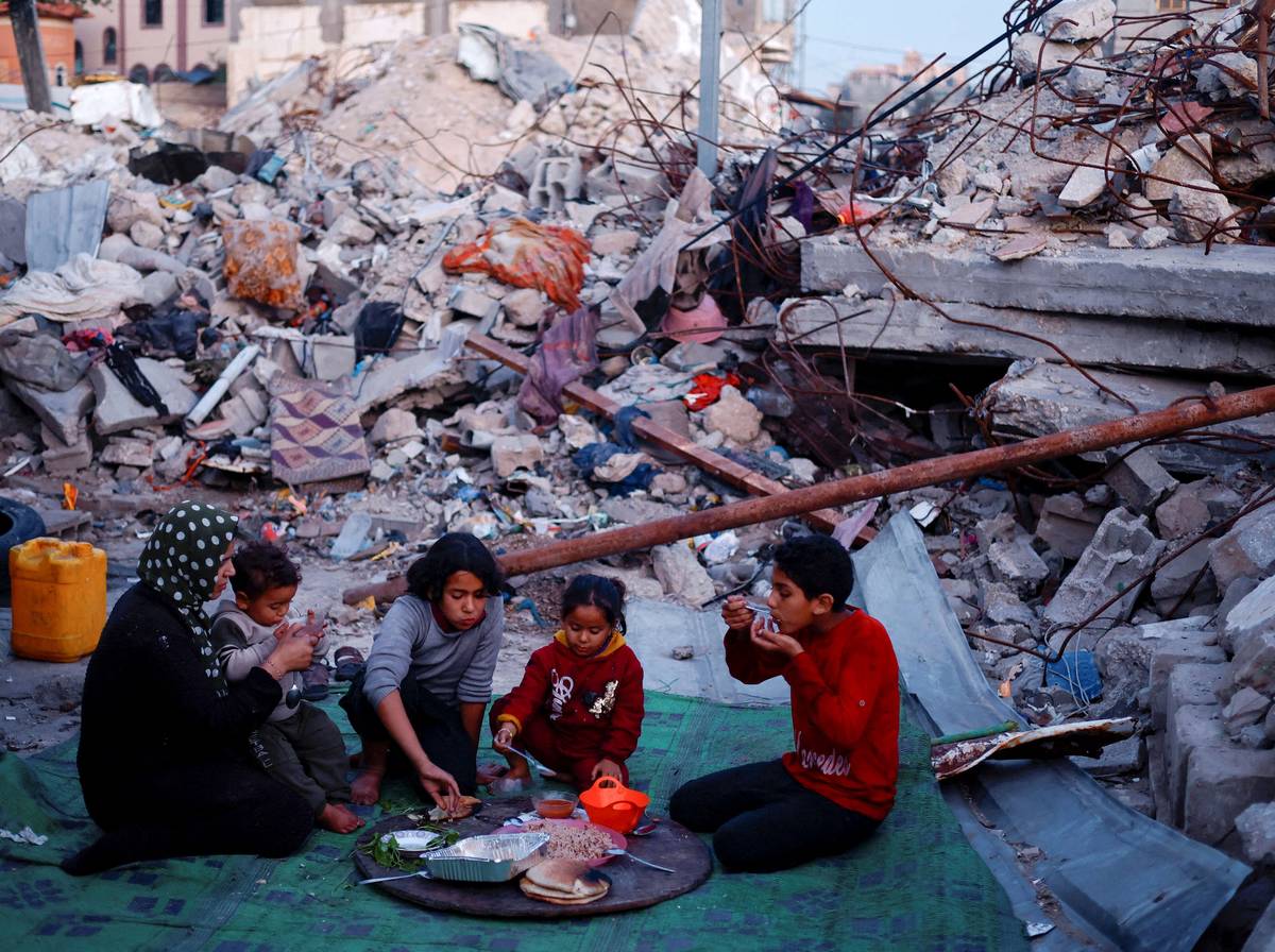عائلة فلسطينية تتناول طعام الافطار أمام منزلها المدمر في غزة