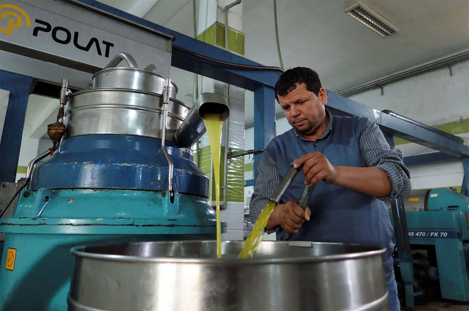 Tunisian olive oil producer, Mustapha Mtiraoui, works inside his oil mill in Kairouan