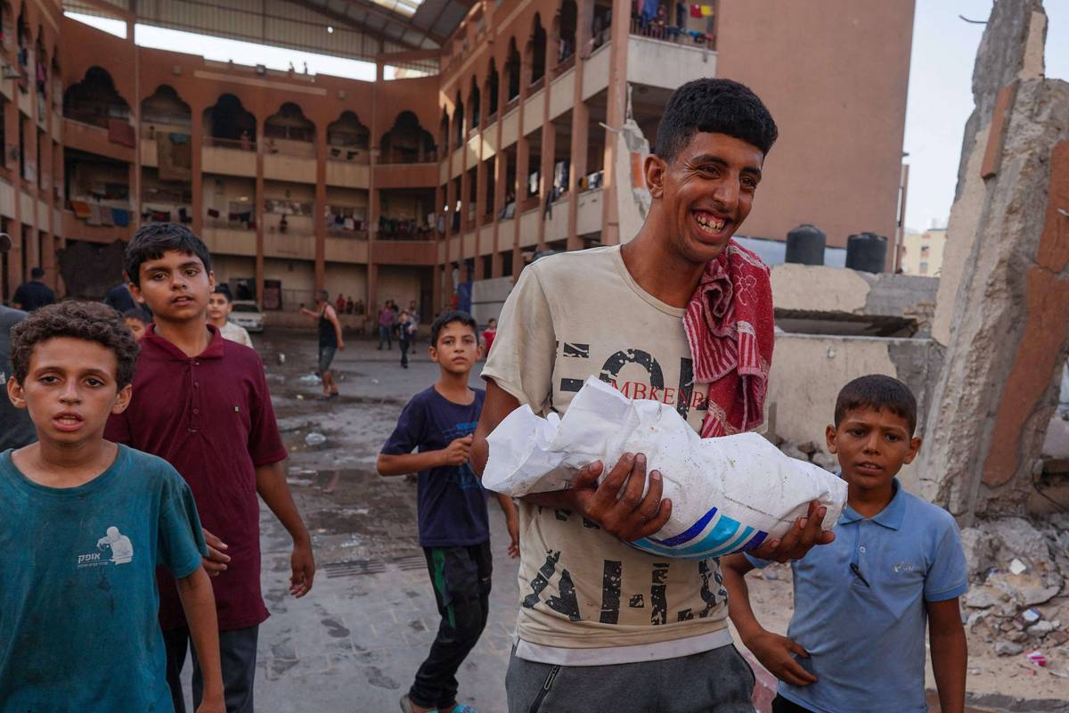 فلسطيني يحمل كيس طحين من الاسقاطات الجوية على خان يونس في غزة