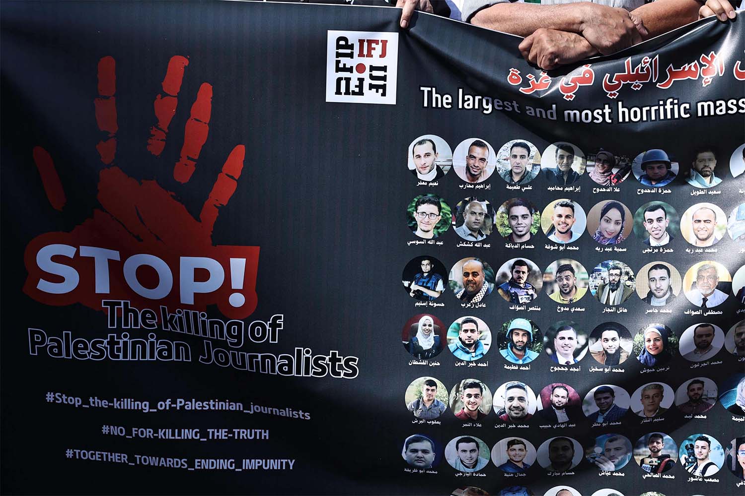 Protesters carry a banner bearing pictures of slain Palestinian journalists during a rally to condemn their killing