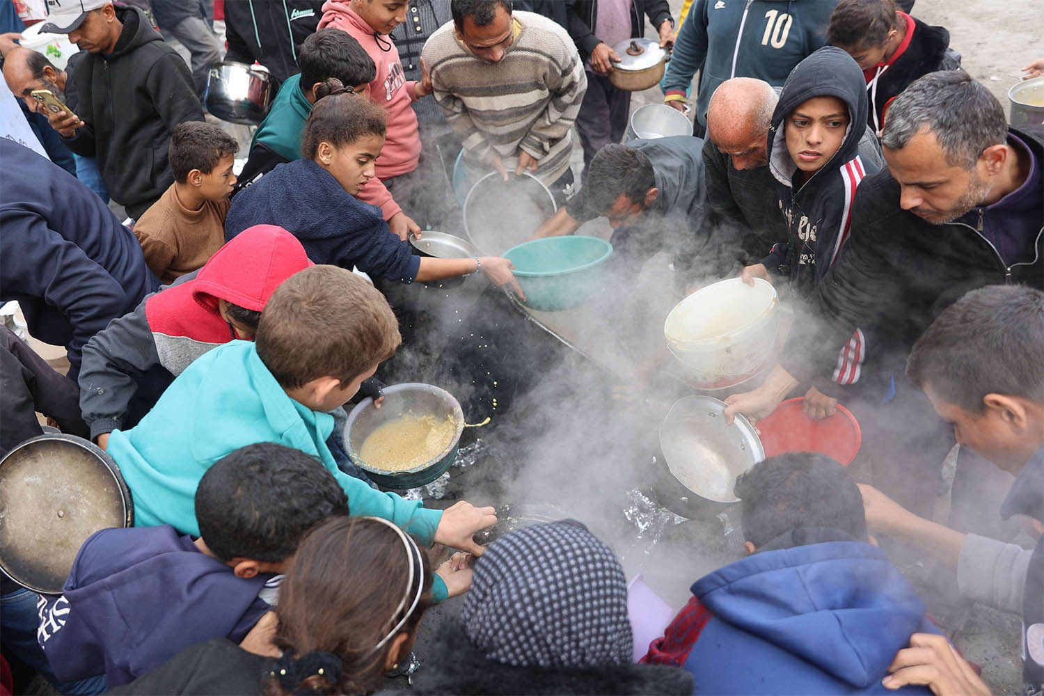 alestinians queue to receive a food ration outside a distribution center west of Gaza City
