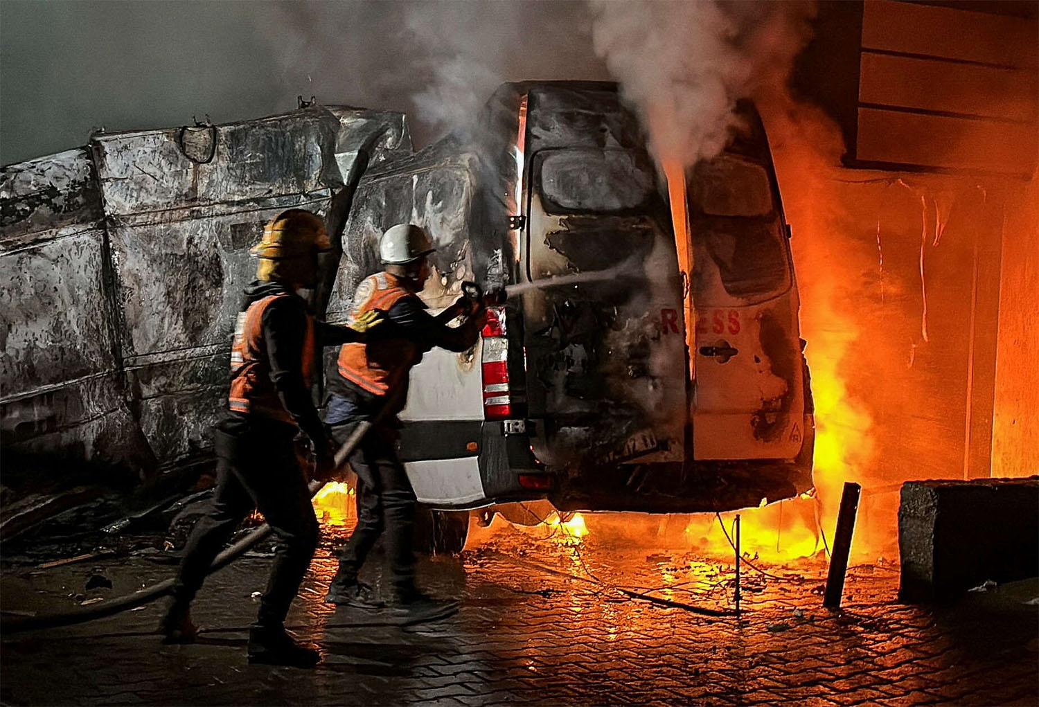 Civil Defense members put out a fire in a broadcast van following an Israeli strike that killed the five journalists