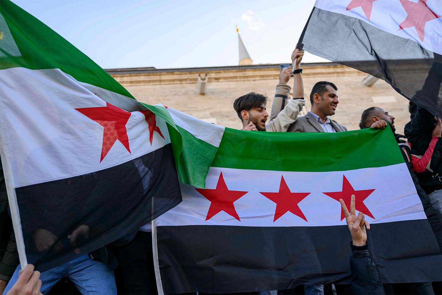 Syrian residents in Turkey hold Syrian flags as they celebrate the end of the Baath rule in Syria 