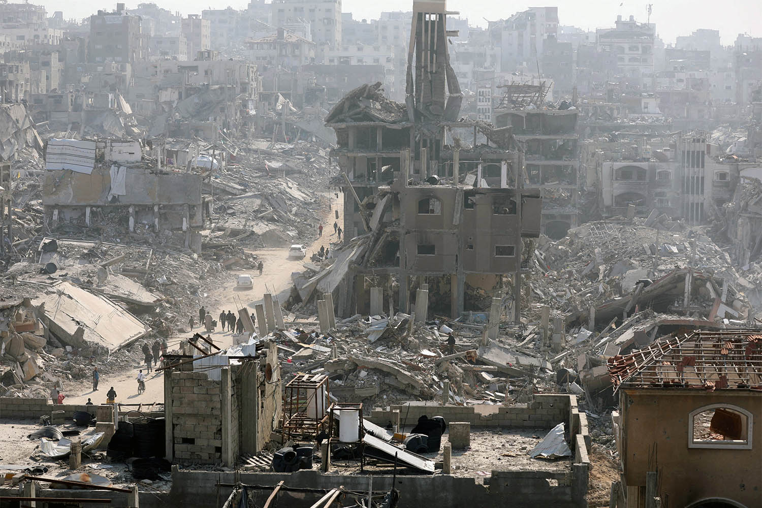 People walk past the rubble of destroyed buildings in Jabalia