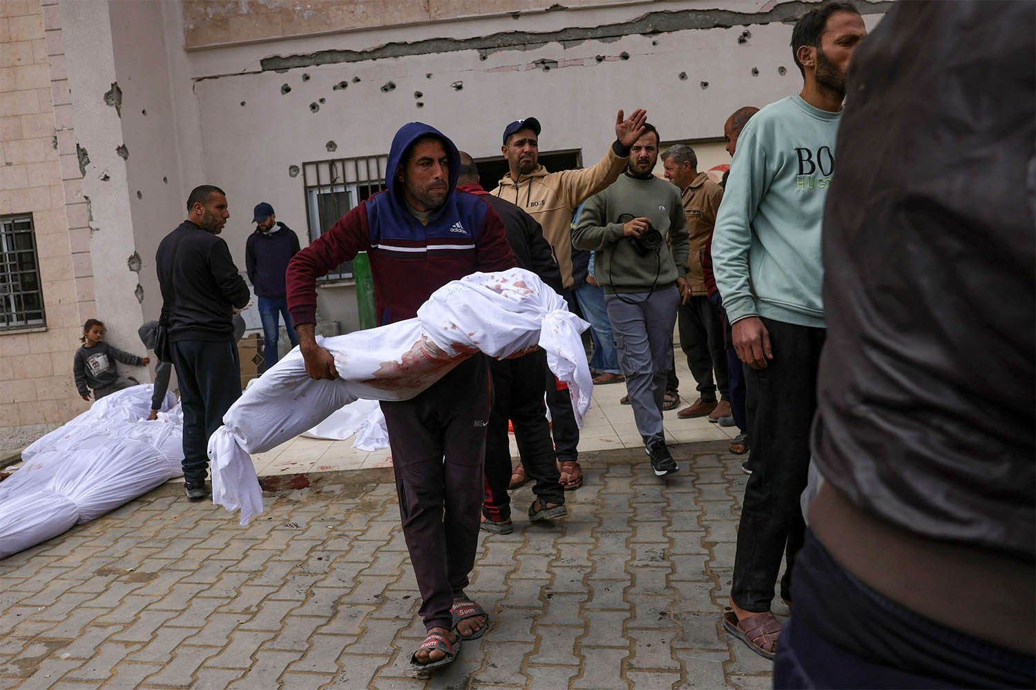 A Palestinian man carries the body of a young victim killed in Israeli overnight airstrikes in the northern Gaza Strip