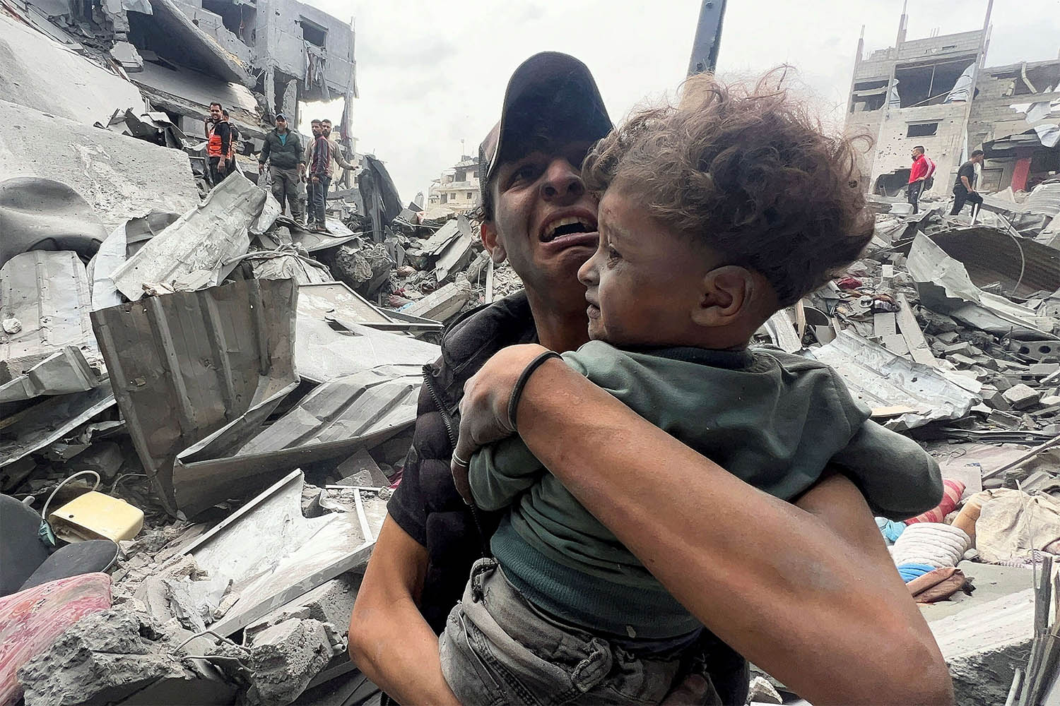 A Palestinian man cries as he holds a child at the site of an Israeli strike on a house in Shejaia in Gaza City