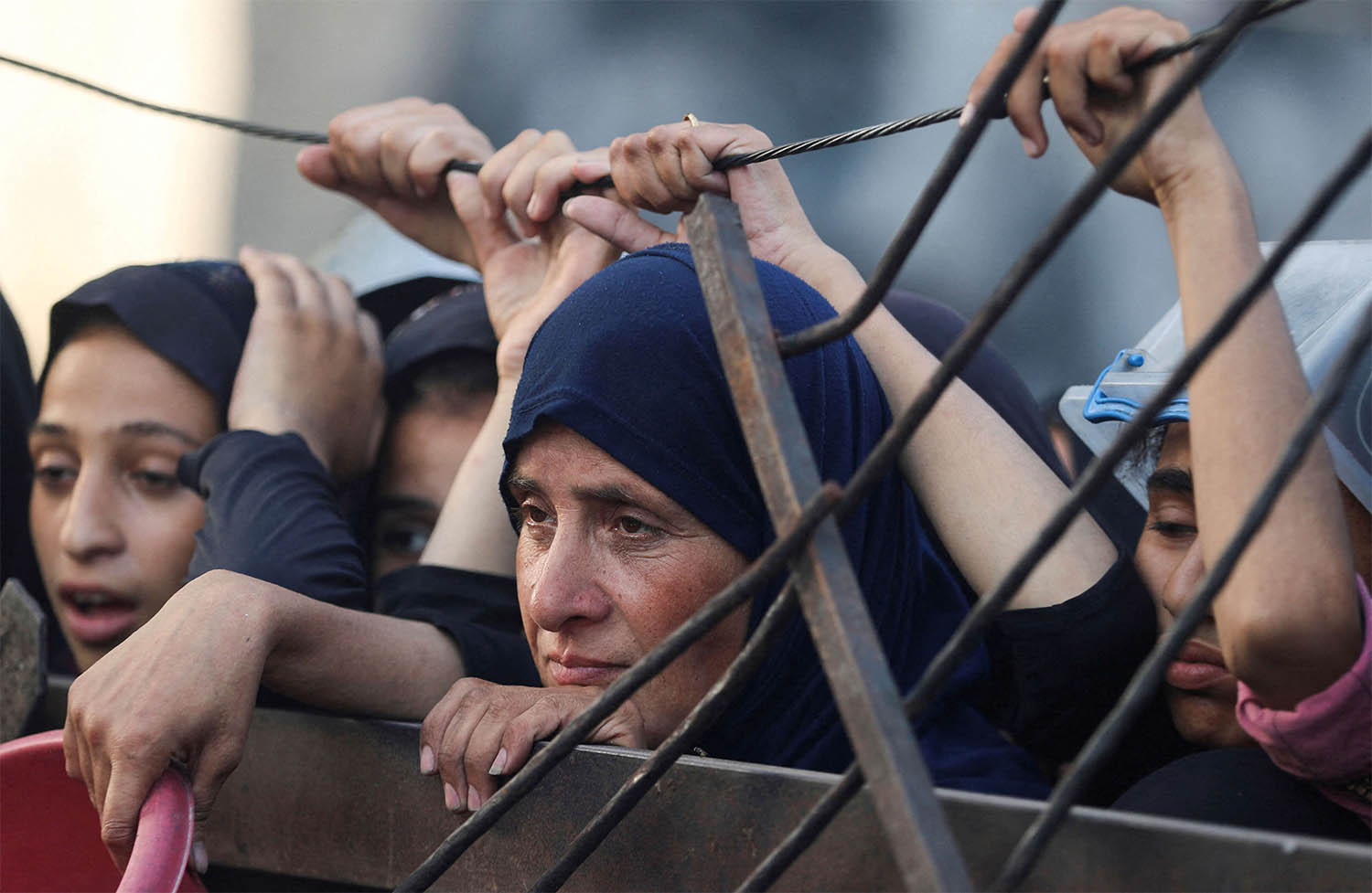Palestinians look on as they wait to receive food from a charity kitchen amid a hunger crisis in Gaza City