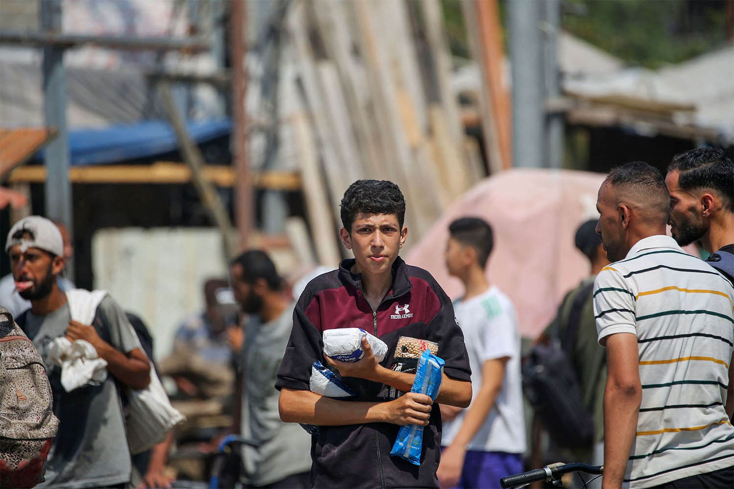  Displaced Palestinians at the Nuseirat refugee camp haul food parcels and other items they managed to get from a GHF aid distribution point at the so-called Netzarim corridor 