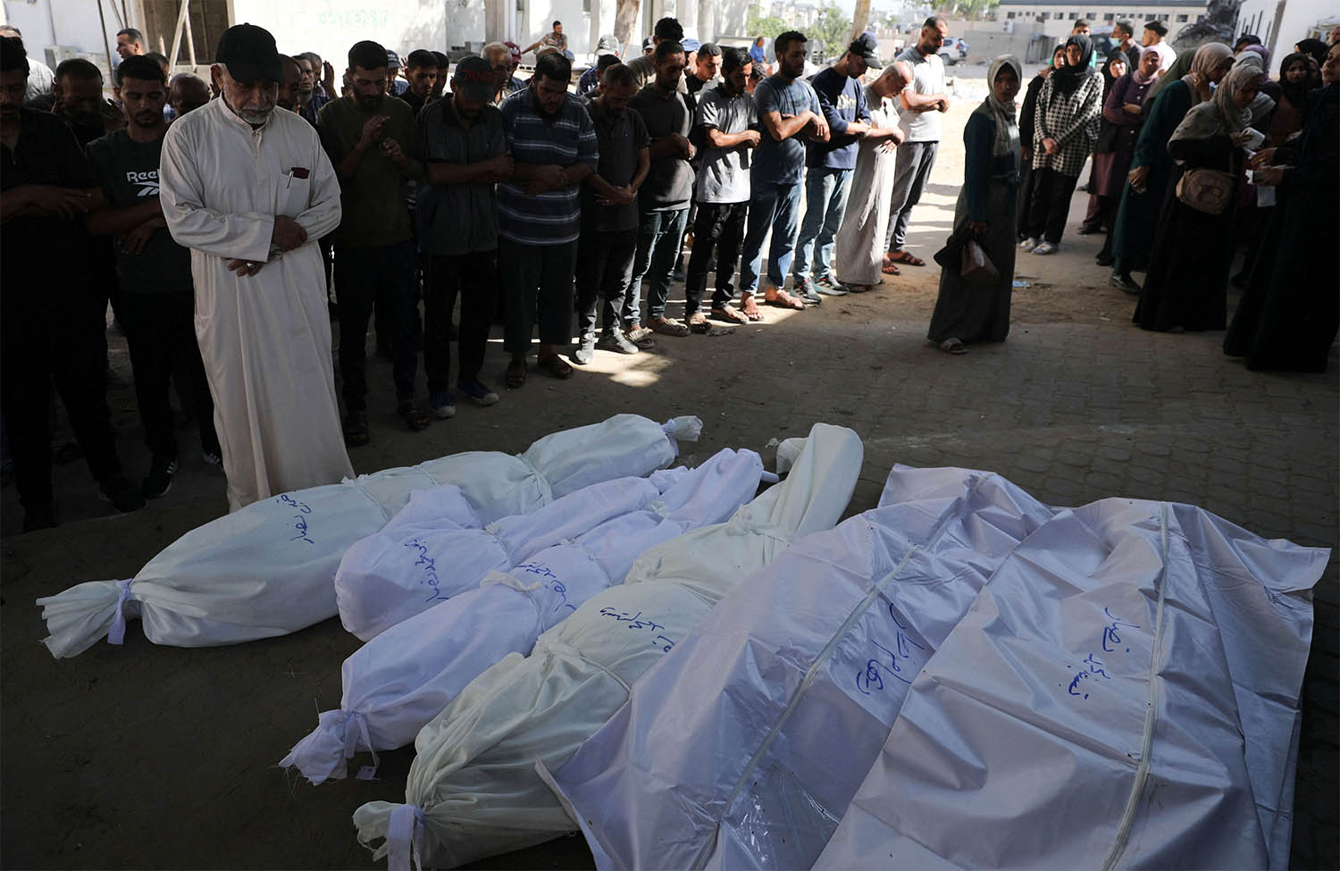 Mourners pray next to shrouded bodies during the funeral of Palestinians killed in an overnight strike on a tent in Gaza City
