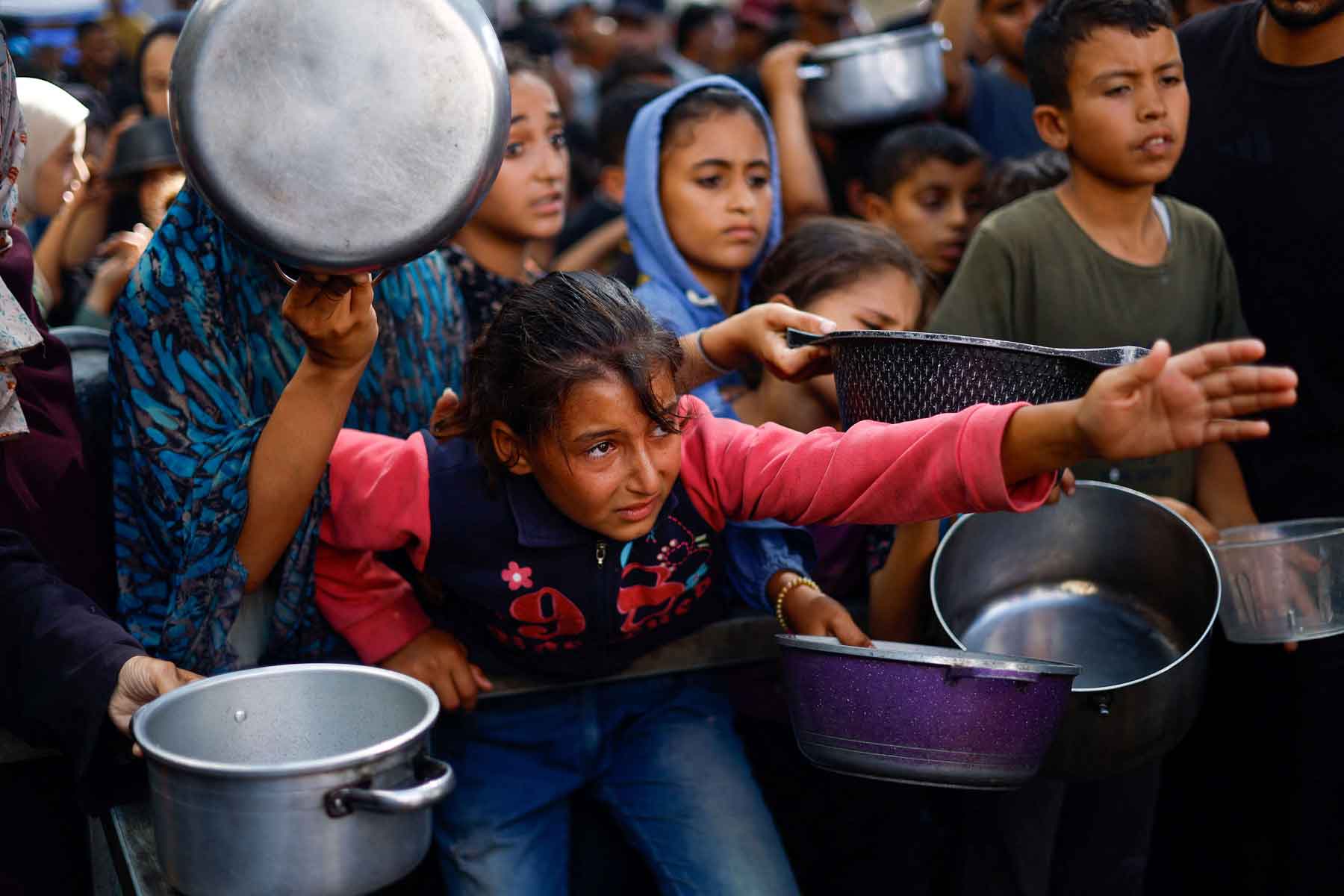 Palestinians gather to receive food from a charity kitchen, in Nuseirat, central Gaza Strip, October 7, 2025. 