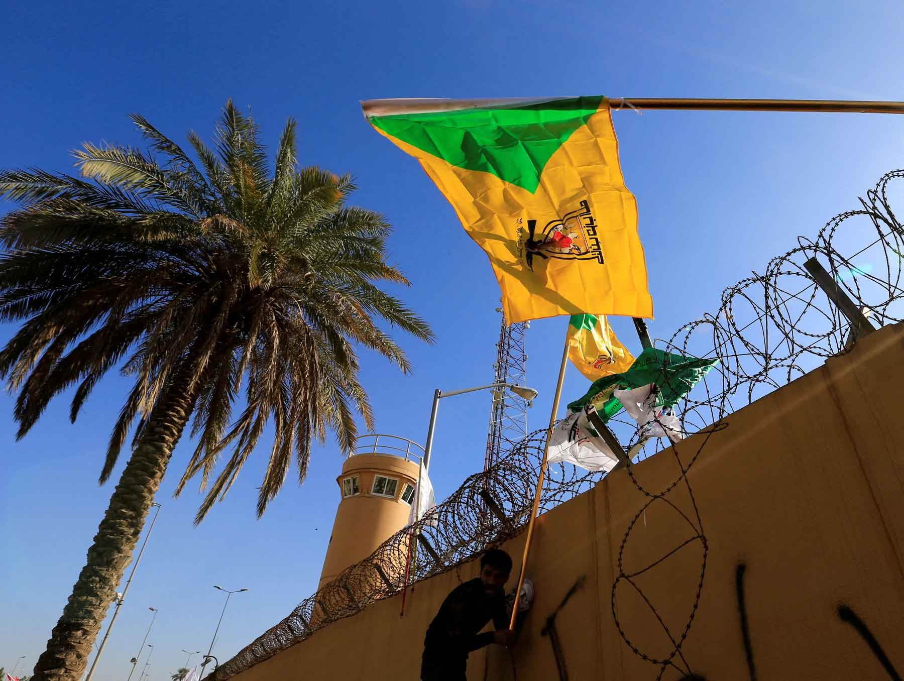 A member of Hashd al-Shaabi (paramilitary forces) holds a flag of Kataib Hezbollah militia group in Baghdad.
