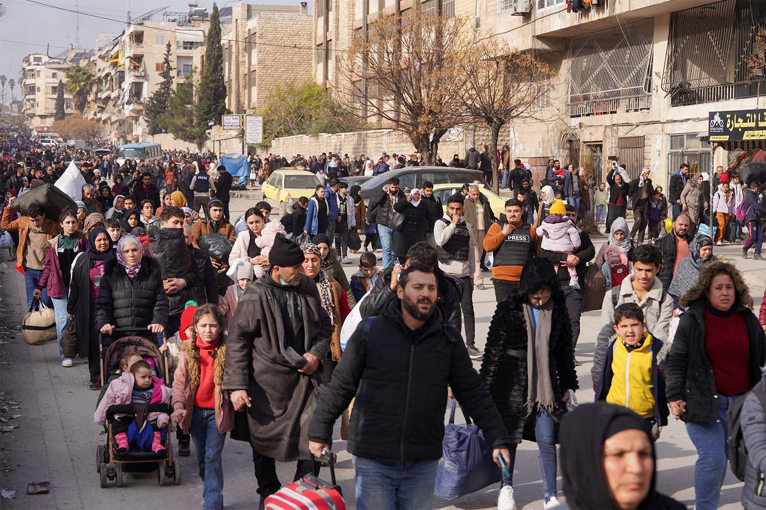 Civilians carry their bags and belongings as they flee following renewed clashes between the Syrian army and the Syrian Democratic Forces in Aleppo