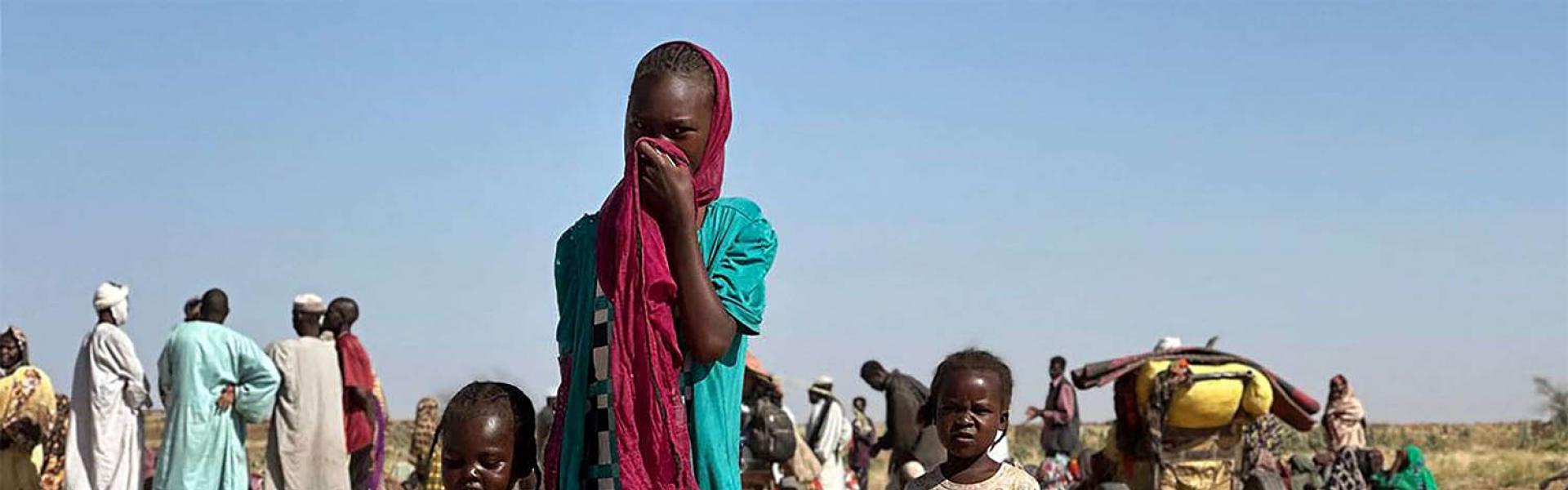 A displaced Sudanese woman, accompanied by children, walks at a camp near the town of Tawila in North Darfur