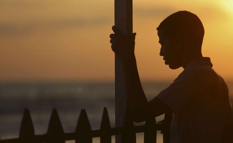 فتى فلسطيني يتطلع إلى المغيب على شاطئ غزة