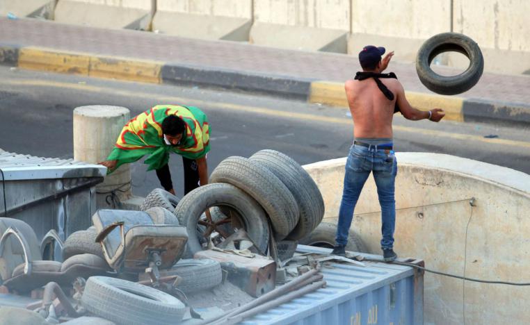 عراقي يلقي بإطارات وسط شارع في مدينة البصرة استعدادا لحرقها
