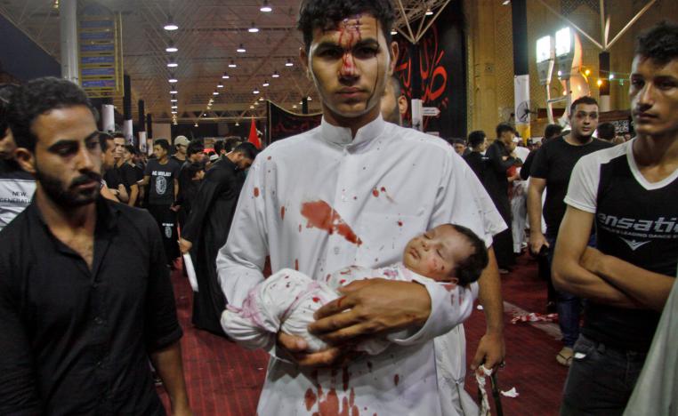 A man holds a baby as Shiite Muslims flagellate themselves during the ten-day mourning period leading up to Ashura, on September 19, 2018 in Iraq's holy city of Najaf.