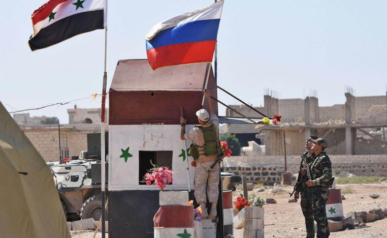 جندي روسي يرفع علم بلاده إلى جانب العلم السوري في أبو الظهور بالقرب من إدلب