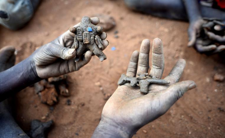 Displaced child holds clay model toys of a peacekeeper and a rifle in Juba, South Sudan.