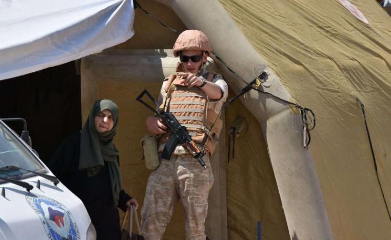  A Russian soldier guides a Syrian woman at the Abu Duhur crossing on the eastern edge of Idlib province, on August 20. 