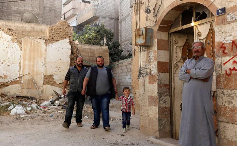 أحمد الكردي أمام منزله رفقة ابنيه وحفيده