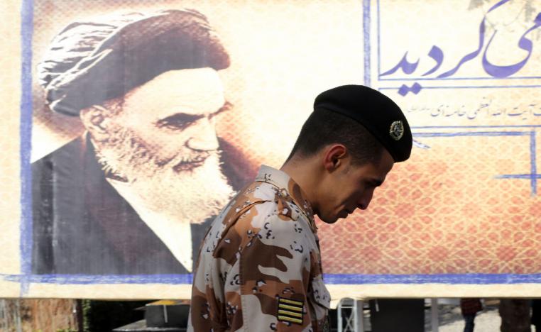 An Iranian soldier walks past a giant board displaying a portrait of the late founder of the Islamic Revolution Ayatollah Ruhollah Khomeini.