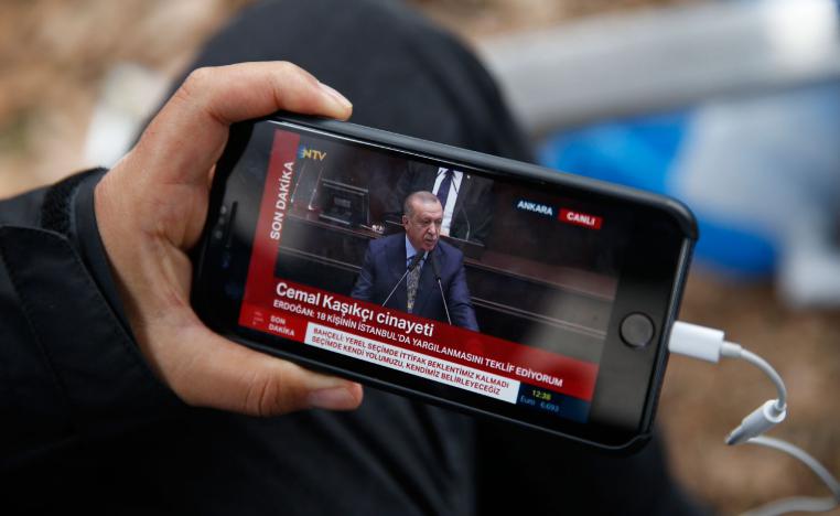 A journalist covering the killing of Saudi writer Jamal Khashoggi, watches a live transmission of Turkey's President Recep Tayyip Erdogan addressing members of his ruling Justice and Development Party (AKP), at the parliament in Ankara, Turkey, Tuesday, Oct. 23, 2018.