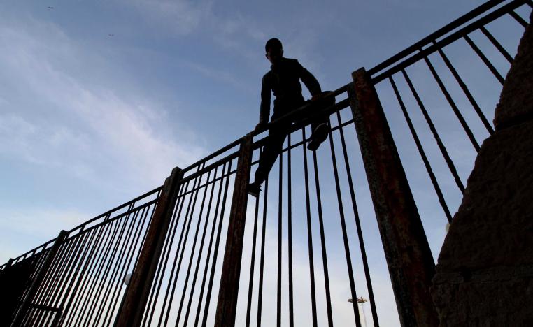 Moroccan youngster climbs a fence in the port of the Spanish enclave of Melilla bordering Morocco