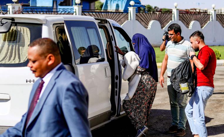 Sudanese woman (C) carrying a one-month-old baby being escorted into a vehicle in Syria's northeastern city of Qamishli.