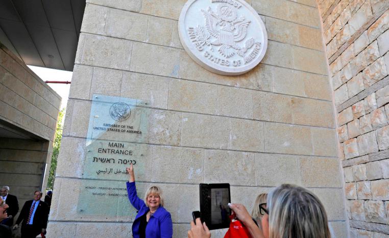A woman poses for a picture next to an inauguration plaque during the opening of the US embassy in occupied Jerusalem.