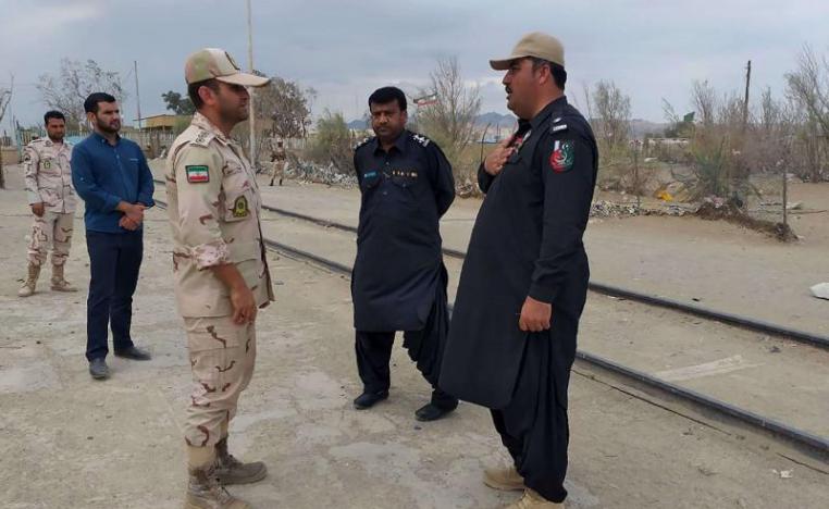 A Pakistani border security official (R) and an Iranian border official meet at Zero Point in the Pakistan-Iran border town of Taftan, on October 16