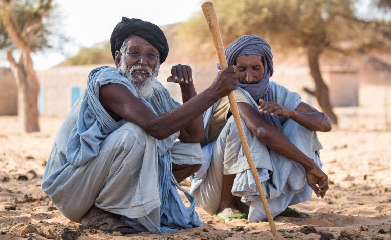 Men sit on the ground in Ouad Initi, eastern Mauritania, on November 21, 2018.