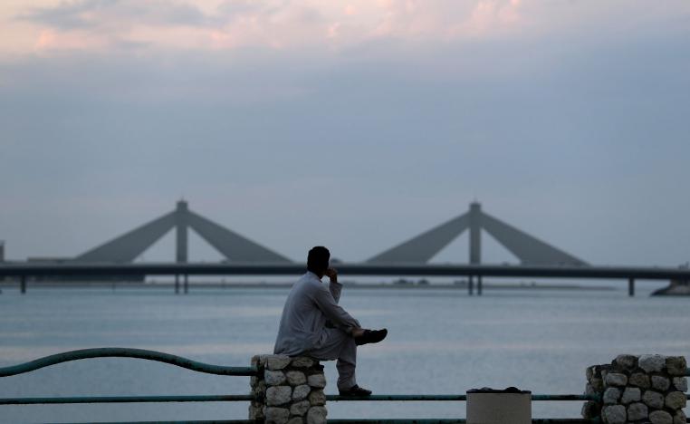 A man sits and looks towards the Sheikh Isa Causeway, linking Diplomatic Area to Muharraq, during the early evening hours in Manama, Bahrain, November 11, 2018.