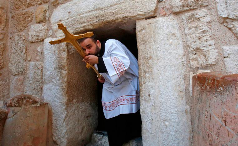 A Latin clergy carries a cross at the Church of the Nativity in the West Bank city of Bethlehem on December 24, 2018.