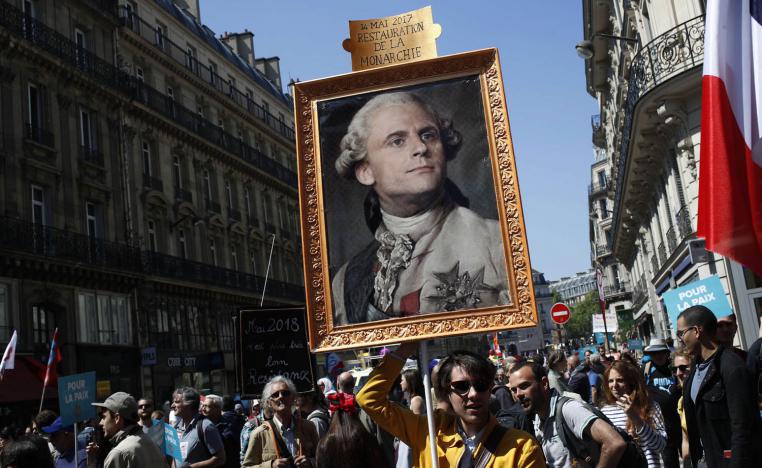 متظاهرون يرفعون صورة مركبة للرئيس إيمانويل ماكرون على لوحة لملك فرنسا لويس السادس عشر