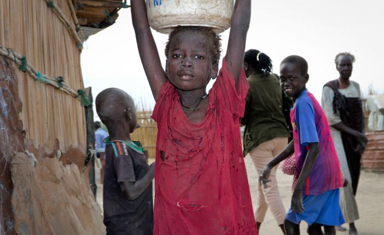 A young girl carries water on her head in Koythiey displaced person's camp on the outskirts of Bentiu town in South Sudan.