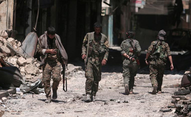 Syria Democratic Forces (SDF) fighters walk on the rubble of damaged shops and buildings in the city of Manbij.