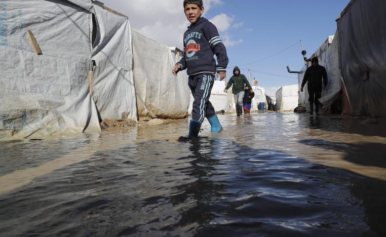 A child wades through rain and snow waters at an informal tent settlement housing Syrian refugees following winter storms in the area of Delhamiyeh, in the central Bekaa Valley on January 17, 2019.