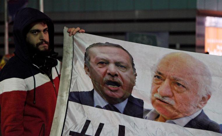 A demonstrator hold pictures of Turkey's Prime Minister Tayyip Erdogan and Turkish cleric Fethullah Gulen.