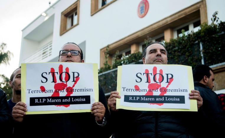 Moroccans holds placards as people pay tribute to murdered Danish Louisa Vesterager Jespersen and Norwegian Maren Ueland in Rabat, in front the Danish ambassy on December 22, 2018.