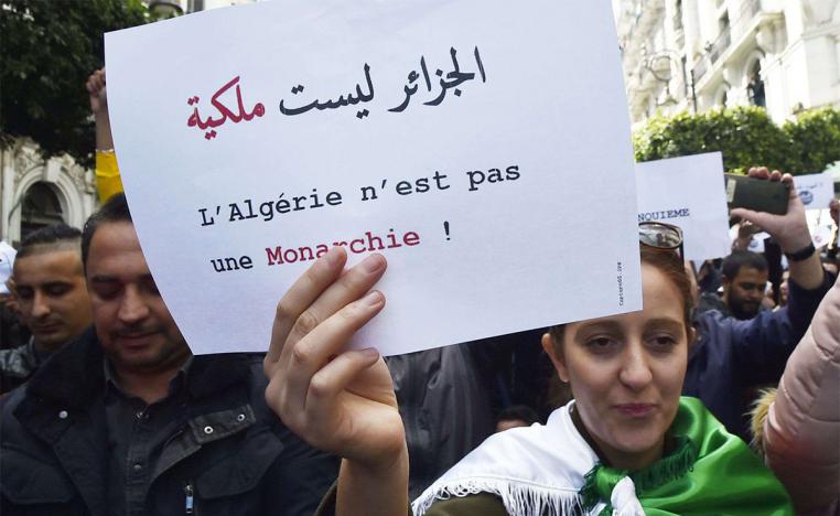 An Algerian protester holds a sign which reads in Arabic and French: "Algeria is not a monarchy" 