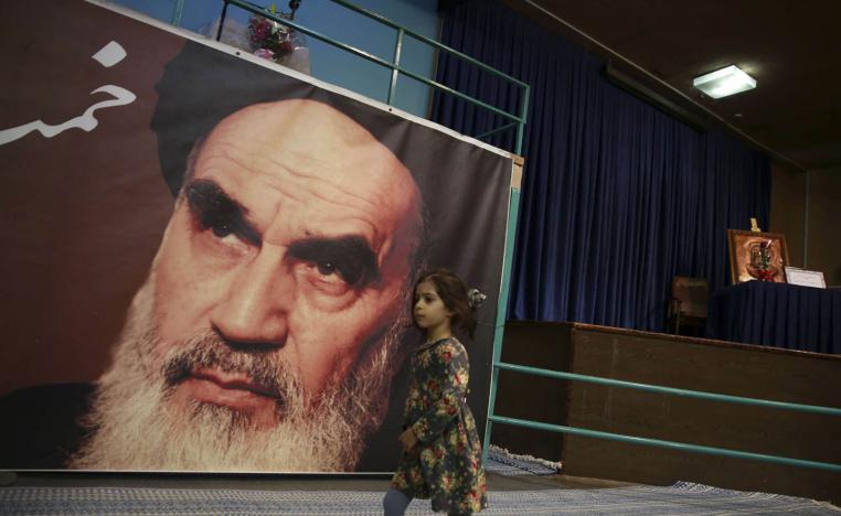 طفلة تمر بجانب صورة الخميني في طهران
