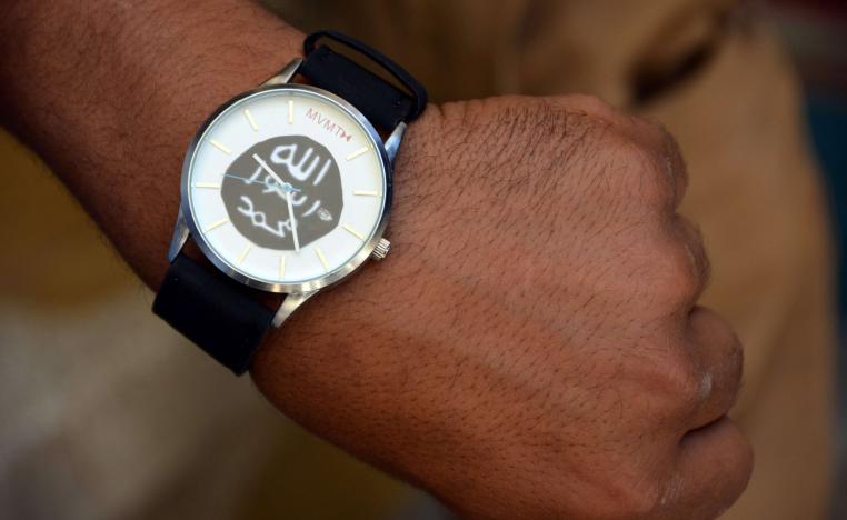 A member of the Iraqi special forces puts on a watch belonging to a former Islamic State (IS) group fighter, bearing the group's logo, found by security forces in the Old City of Mosul, in the city's western industrial district on June 29, 2017.
