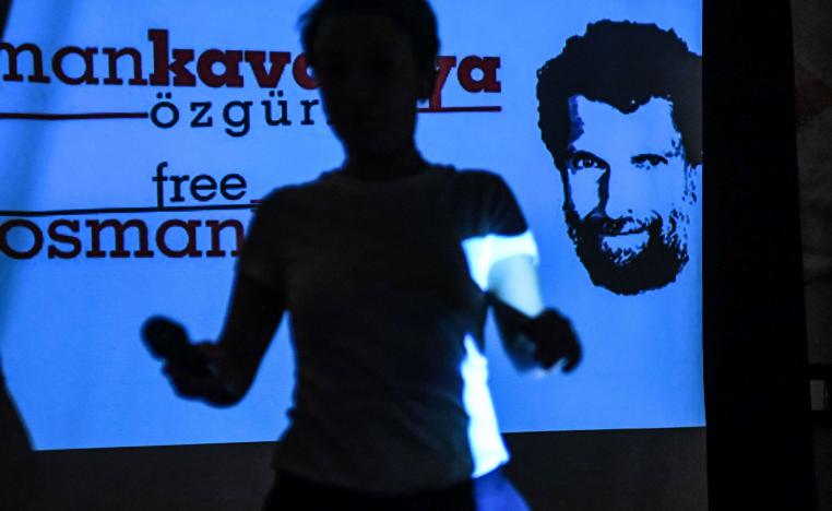 A woman passes in front of a screen featuring jailed businessman and philanthropist Osman Kavala during a press conference of his lawyers on October 31, 2018.