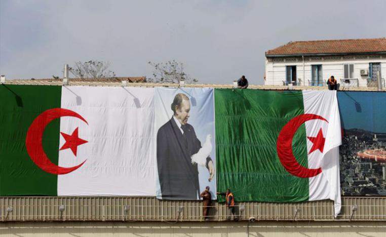 Algerian city employees install national flags and a poster of President Abdelaziz Bouteflika on a street in Algiers.