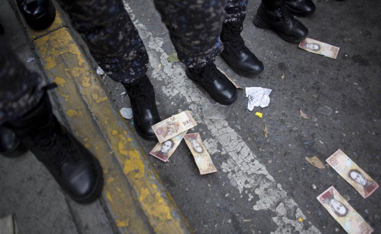 متظاهرون يلقون أوراق نقدية تحت اقدام جنود خرجوا لمنع التظاهرات في كراكاس