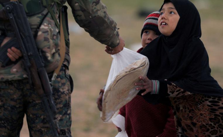 A girl takes a stack of bread from a fighter of Syrian Democratic Forces (SDF) near the village of Baghouz, Deir Al Zor province, Syria February 27, 2019.