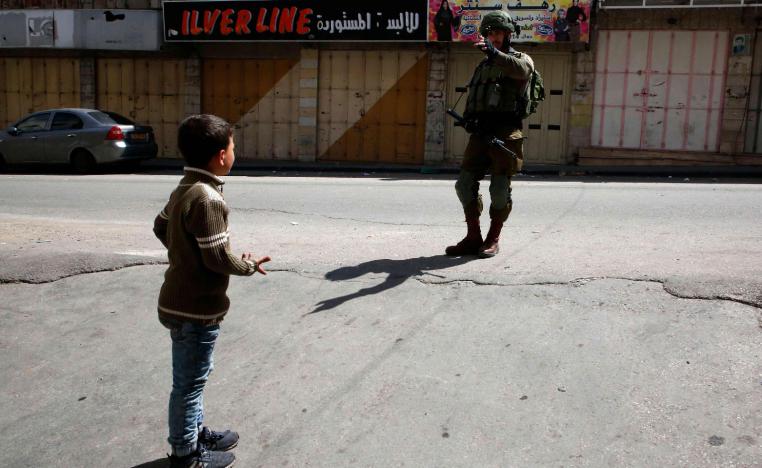 A Palestinian boy is denied access to a street by an Israeli soldier in the occupied West Bank city of Hebron on March 2, 2018, as it's closed for the visit of Jewish settlers to what they believe is the tomb of biblical figure Othniel Ben Kenaz.