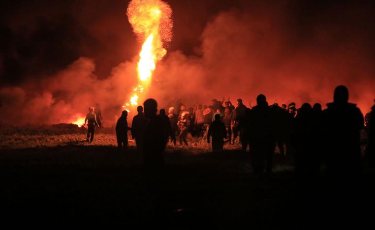 Palestinians watch as an object burns during night clashes between Palestinian demonstrators and Israeli security forces along the Israel-Gaza fence.