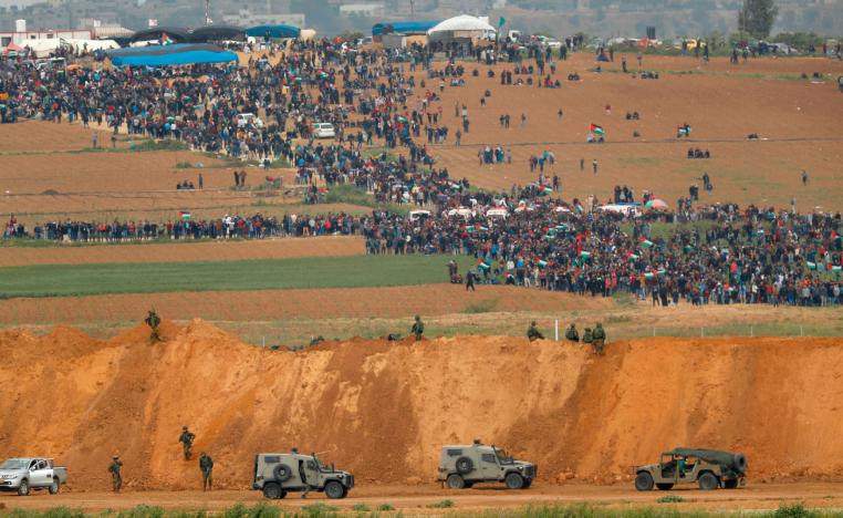 In this file photo taken on March 30, 2018 from the southern Israeli kibbutz of Nahal Oz across the border from the Gaza Strip, Palestinians participating in a tent city protest commemorating Land Day, with Israeli military vehicles seen below in the foreground.