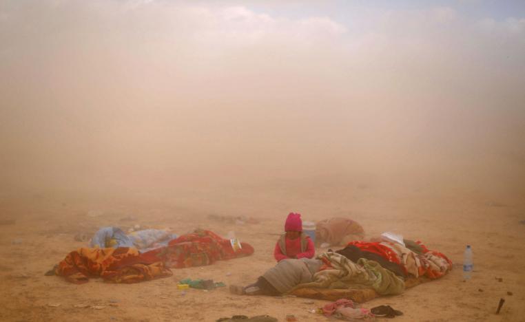 Children sit next to their injured mother near the village of Baghouz, Deir Ezzor province, in Syria March 7, 2019.